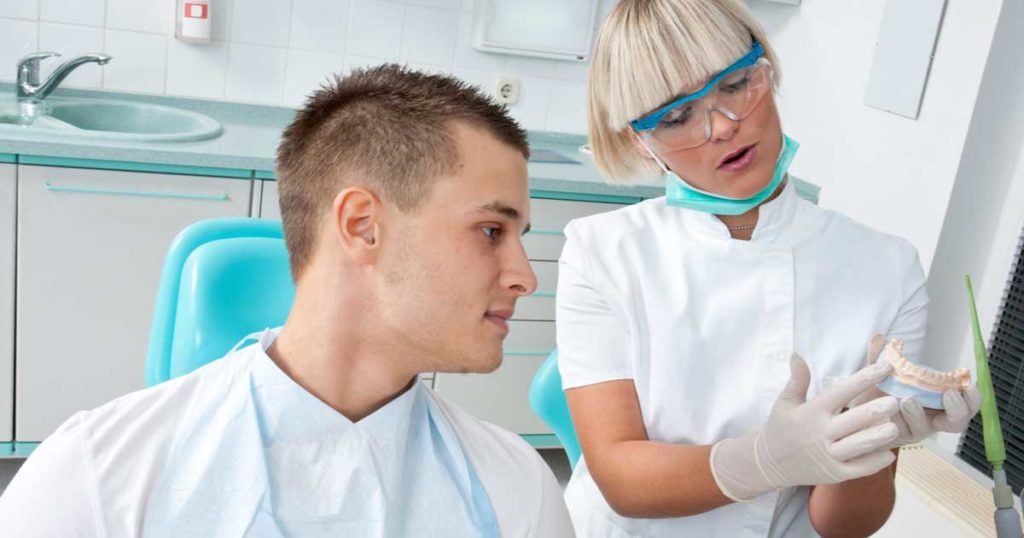 Hygienist Showing Tooth Model for Implants